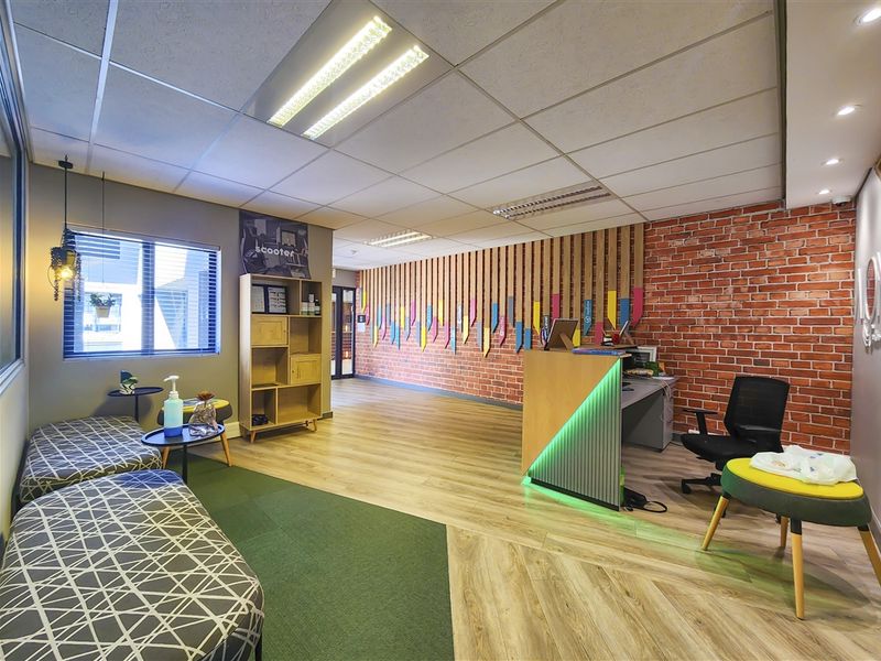 Modern office reception area featuring a built-in desk, exposed brick wall, timber slat accents, and professional suspended ceiling lighting.