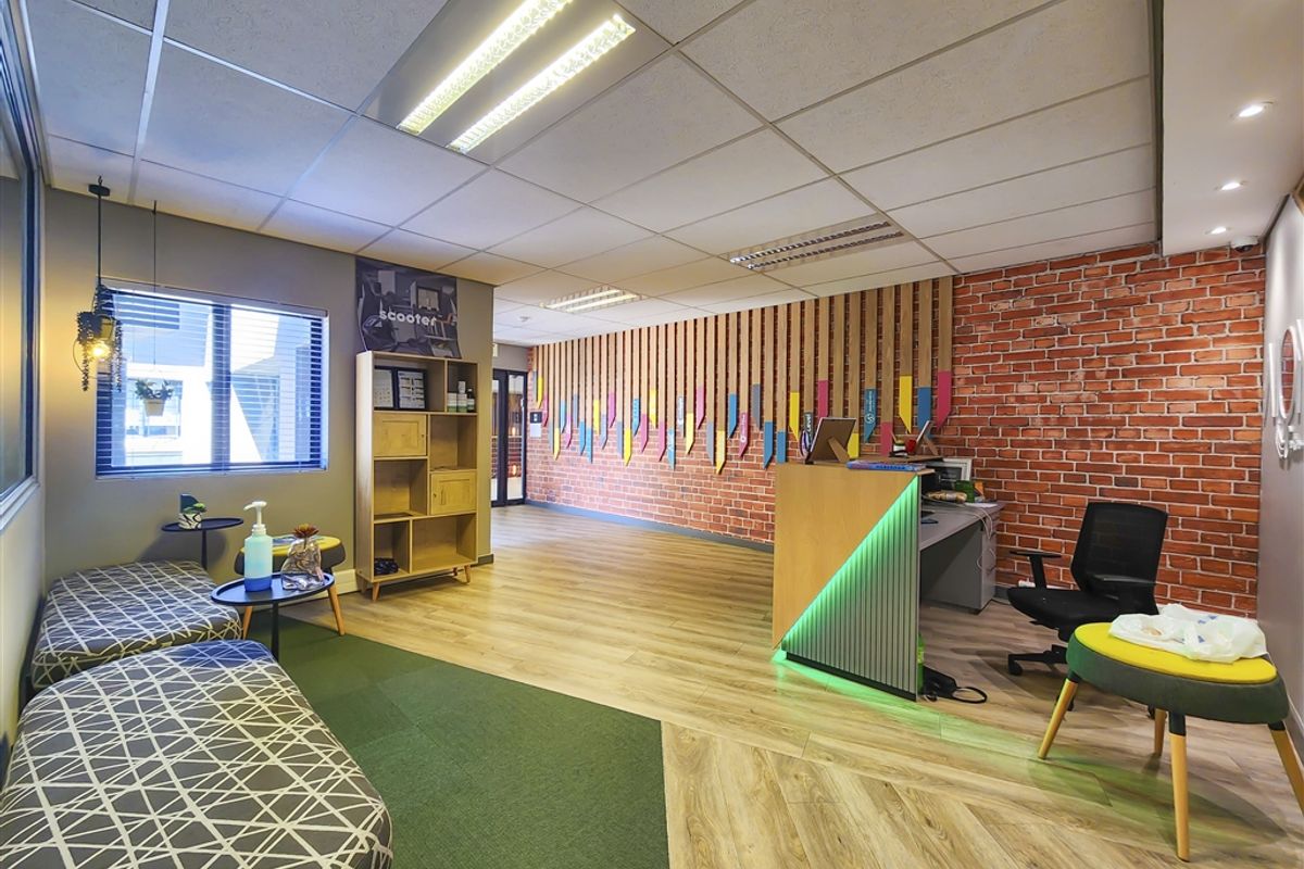 Modern office reception area featuring a built-in desk, exposed brick wall, timber slat accents, and professional suspended ceiling lighting.