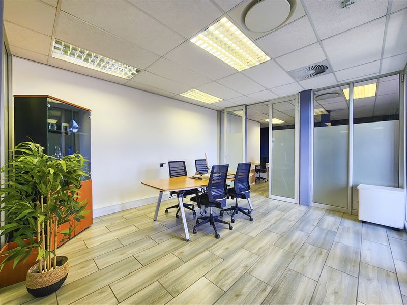A professional office space featuring wood-look tile flooring, suspended ceilings with recessed lighting, and modern glass partition walls for a bright, open work environment.