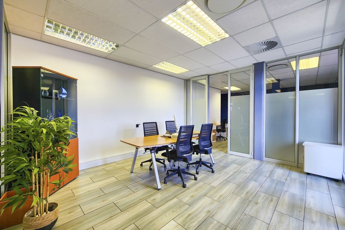 A professional office space featuring wood-look tile flooring, suspended ceilings with recessed lighting, and modern glass partition walls for a bright, open work environment.