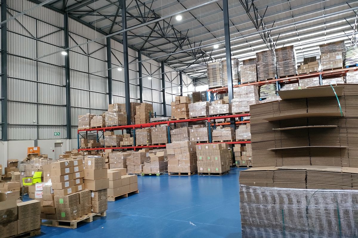 Spacious industrial warehouse featuring high ceilings, steel portal frame construction, durable epoxy flooring, and extensive built-in racking systems for storage.