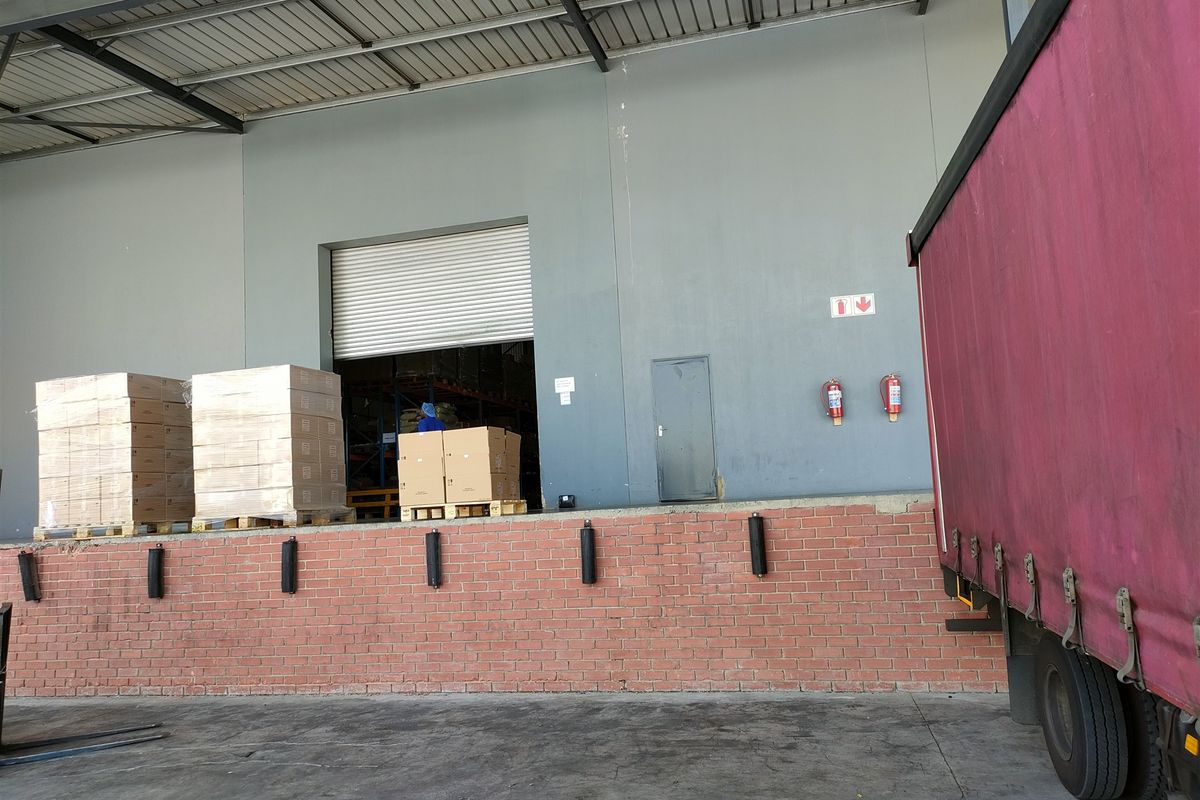 Industrial loading bay area featuring a brick dock, roller shutter door access, and protective dock bumpers under a covered canopy.