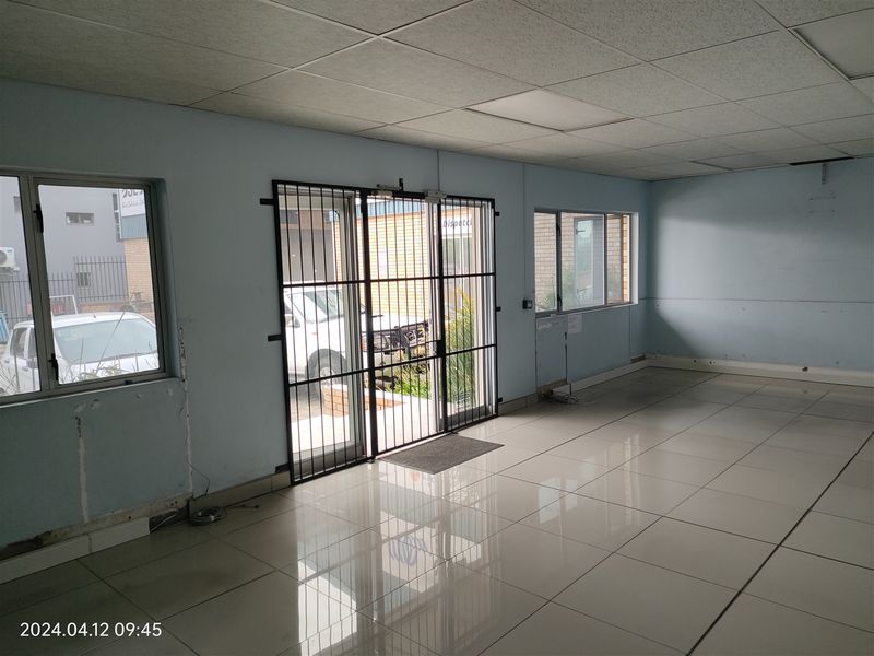 An empty industrial entry area featuring tiled flooring, a drop ceiling, and a secure metal entrance gate.