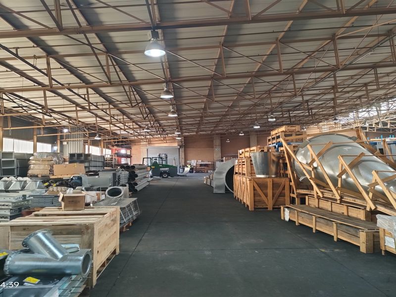 Spacious industrial warehouse facility featuring high-clearance exposed steel roof trusses, durable concrete flooring, and functional overhead industrial lighting.