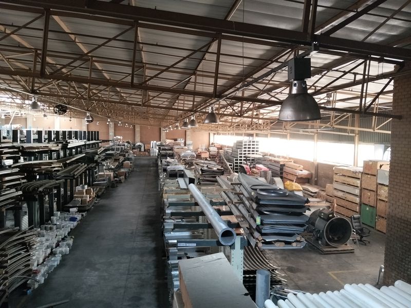 Spacious industrial warehouse facility featuring exposed steel roof trusses, high-bay pendant lighting, and durable concrete flooring, suitable for storage or manufacturing operations.
