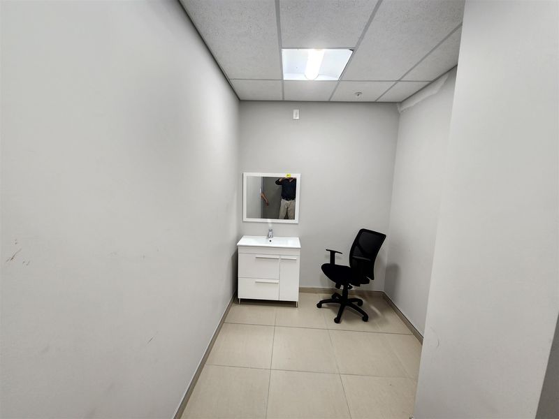 A small office space featuring a built-in vanity with sink, tiled flooring, and a drop ceiling with recessed lighting.
