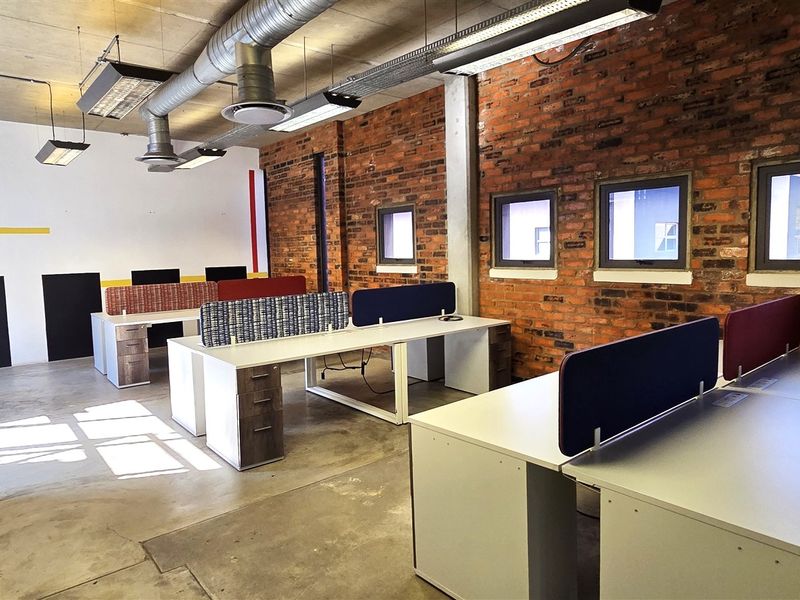 Modern industrial-style office space featuring exposed brick walls, polished concrete floors, and exposed ceiling ducting, providing a contemporary and professional work environment.