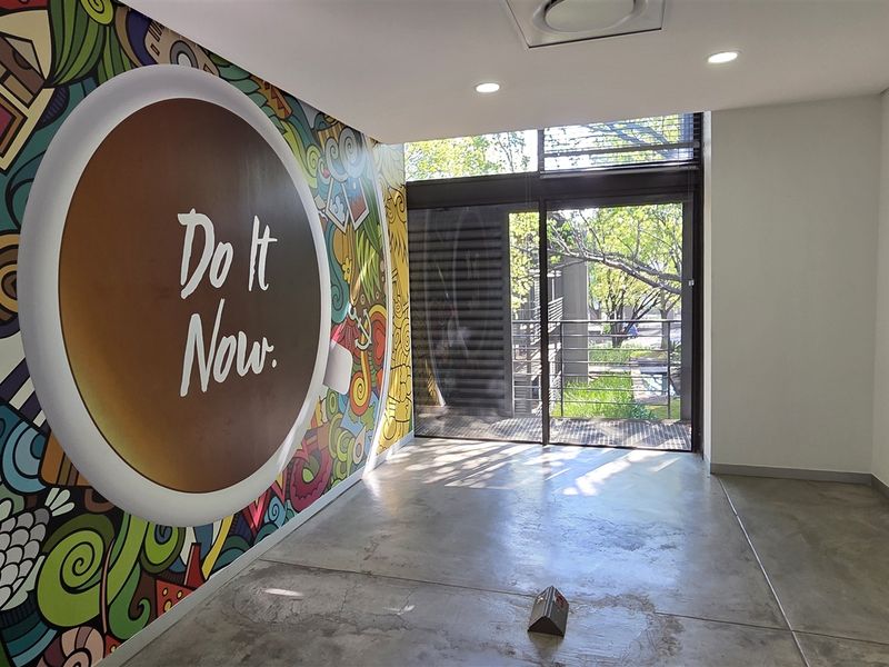 Modern office space featuring polished concrete floors, recessed lighting, and a large sliding glass door providing natural light and outdoor access.