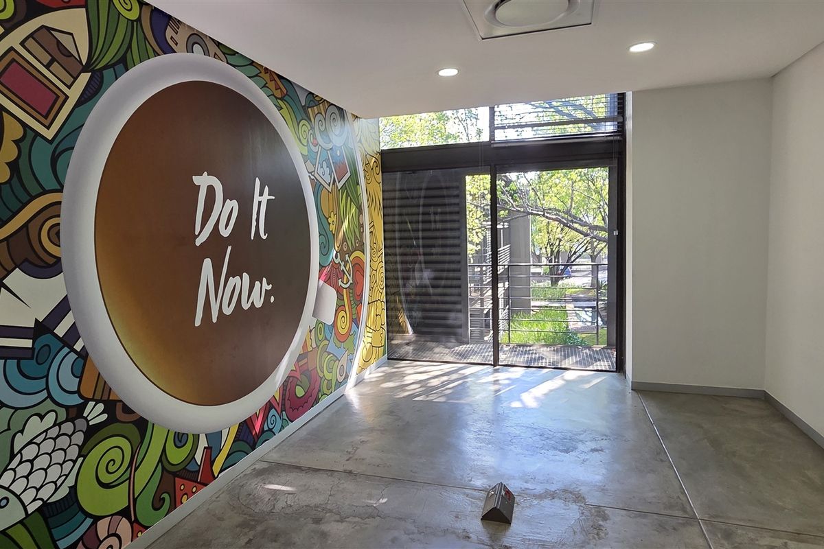 Modern office space featuring polished concrete floors, recessed lighting, and a large sliding glass door providing natural light and outdoor access.