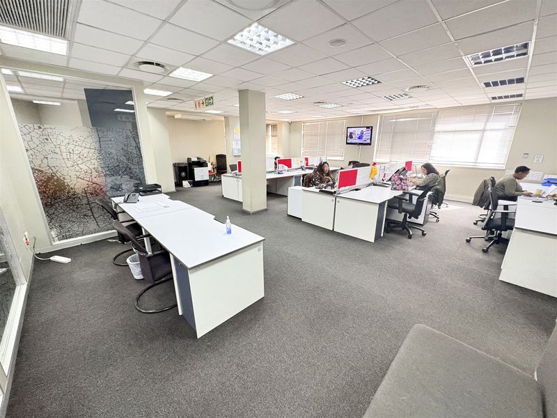 Open-plan office space featuring a suspended ceiling, recessed lighting, carpeted flooring, and a decorative glass partition.