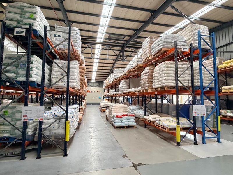 Spacious industrial warehouse facility featuring high-clearance steel roof trusses, translucent skylights, and heavy-duty industrial racking systems on durable epoxy-coated concrete flooring.