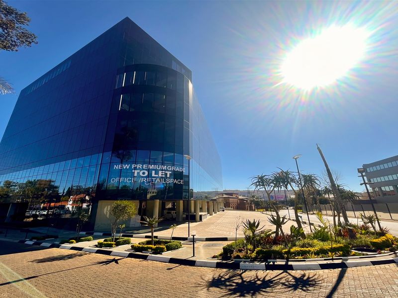 Modern premium-grade office and retail building featuring a sleek glass facade, paved exterior grounds, and professional landscaping.