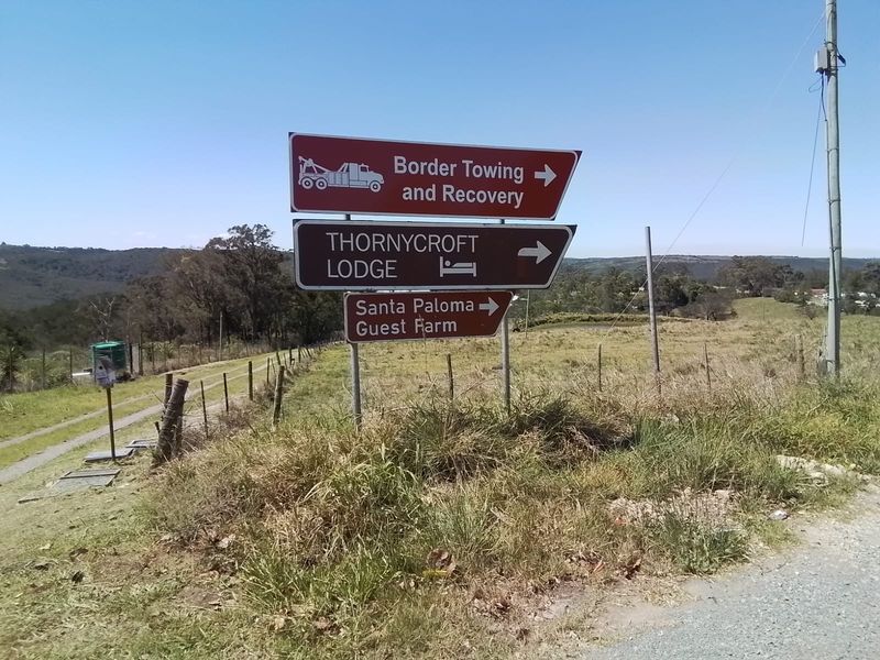 A roadside view showing directional signage for local properties and businesses, including a guest farm, set against a rural landscape.