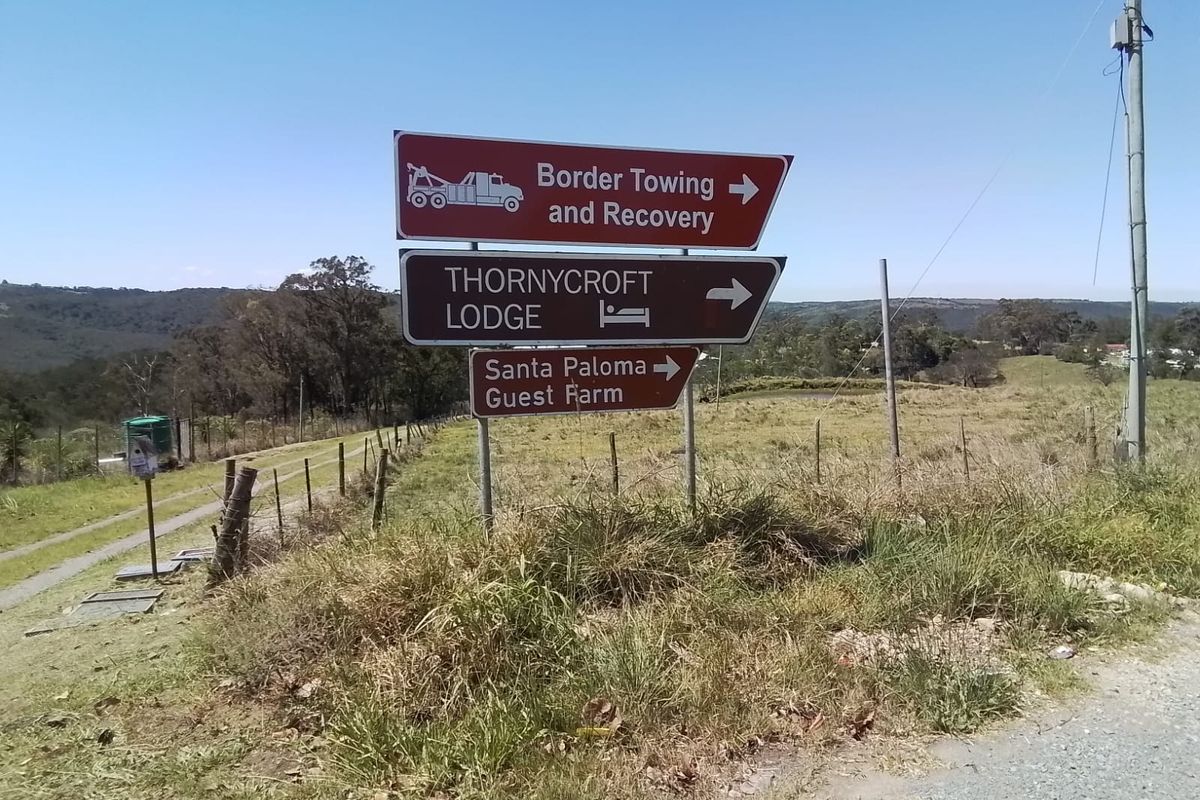 A roadside view showing directional signage for local properties and businesses, including a guest farm, set against a rural landscape.