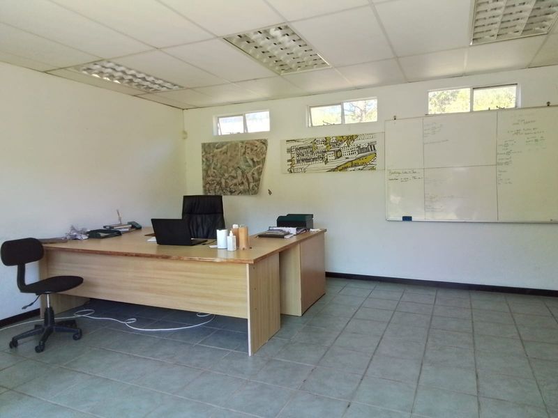 A functional office space featuring a suspended ceiling, tiled flooring, and a large wall-mounted whiteboard, suitable for a professional workspace.