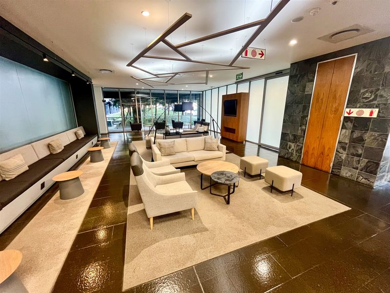 Modern office lounge area featuring built-in bench seating, stone feature wall, and large glass doors providing natural light and outdoor access.