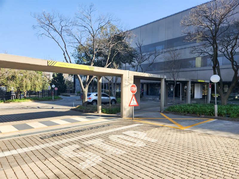 Exterior view of the office property entrance featuring a paved driveway, height restriction barrier, and clear pedestrian access signage.