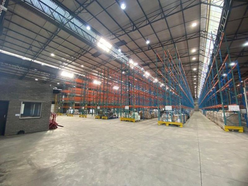 Spacious industrial warehouse featuring high-bay ceilings, durable concrete flooring, and extensive integrated steel racking systems for efficient storage and logistics operations.