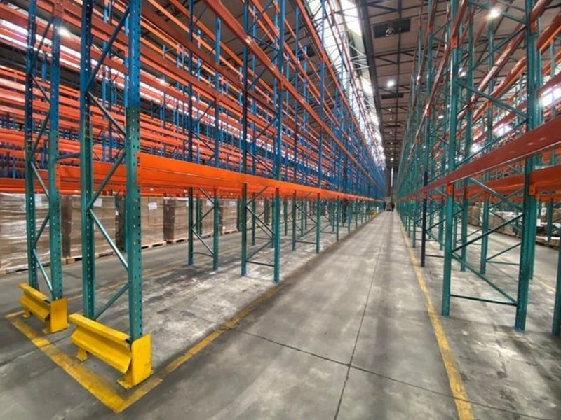 Spacious industrial warehouse interior featuring extensive high-capacity pallet racking systems, durable concrete flooring, and clear safety demarcations for efficient logistics operations.