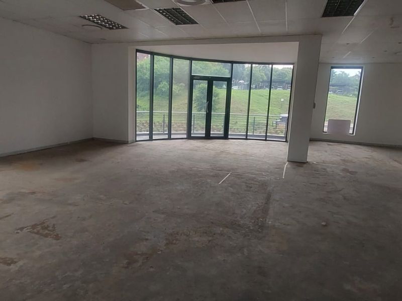 An empty, open-plan office space featuring large windows, natural light, suspended ceilings, and unfinished concrete flooring, ready for custom fit-out.