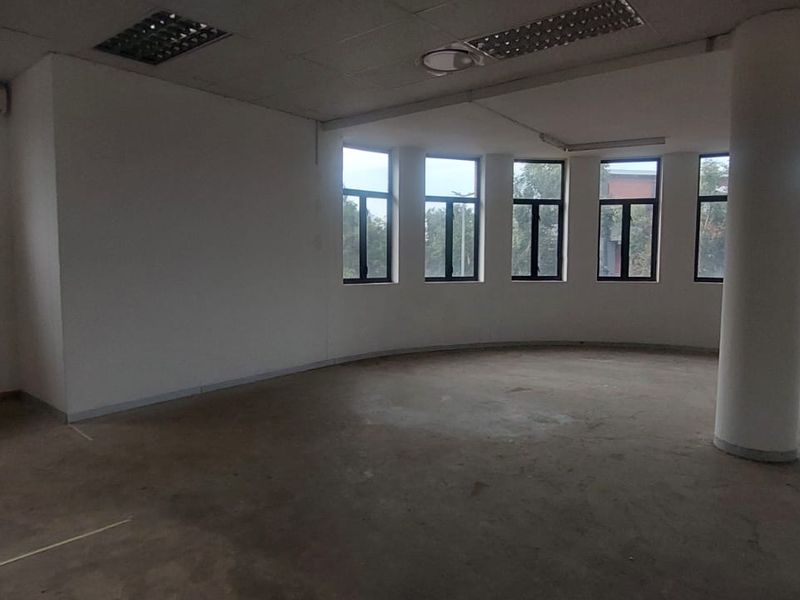 Spacious, open-plan office area featuring large windows, a structural column, and a suspended ceiling, currently in a shell condition ready for fit-out.