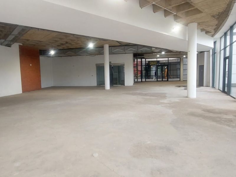 Spacious open-plan retail unit featuring large glass storefront windows, exposed concrete ceilings, and structural columns, offering a blank canvas for custom fit-out.