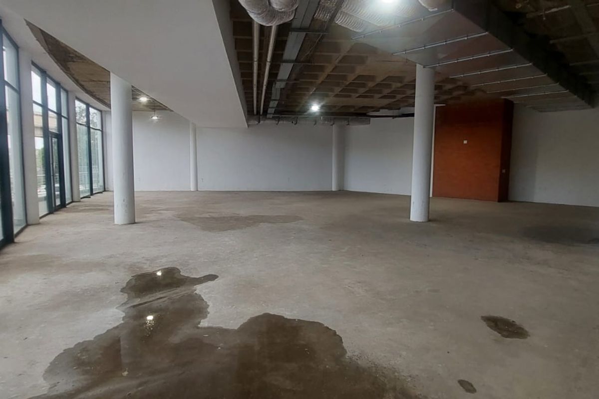 Expansive open-plan retail space featuring exposed industrial ceilings, structural columns, and floor-to-ceiling glass windows, currently in a shell condition.