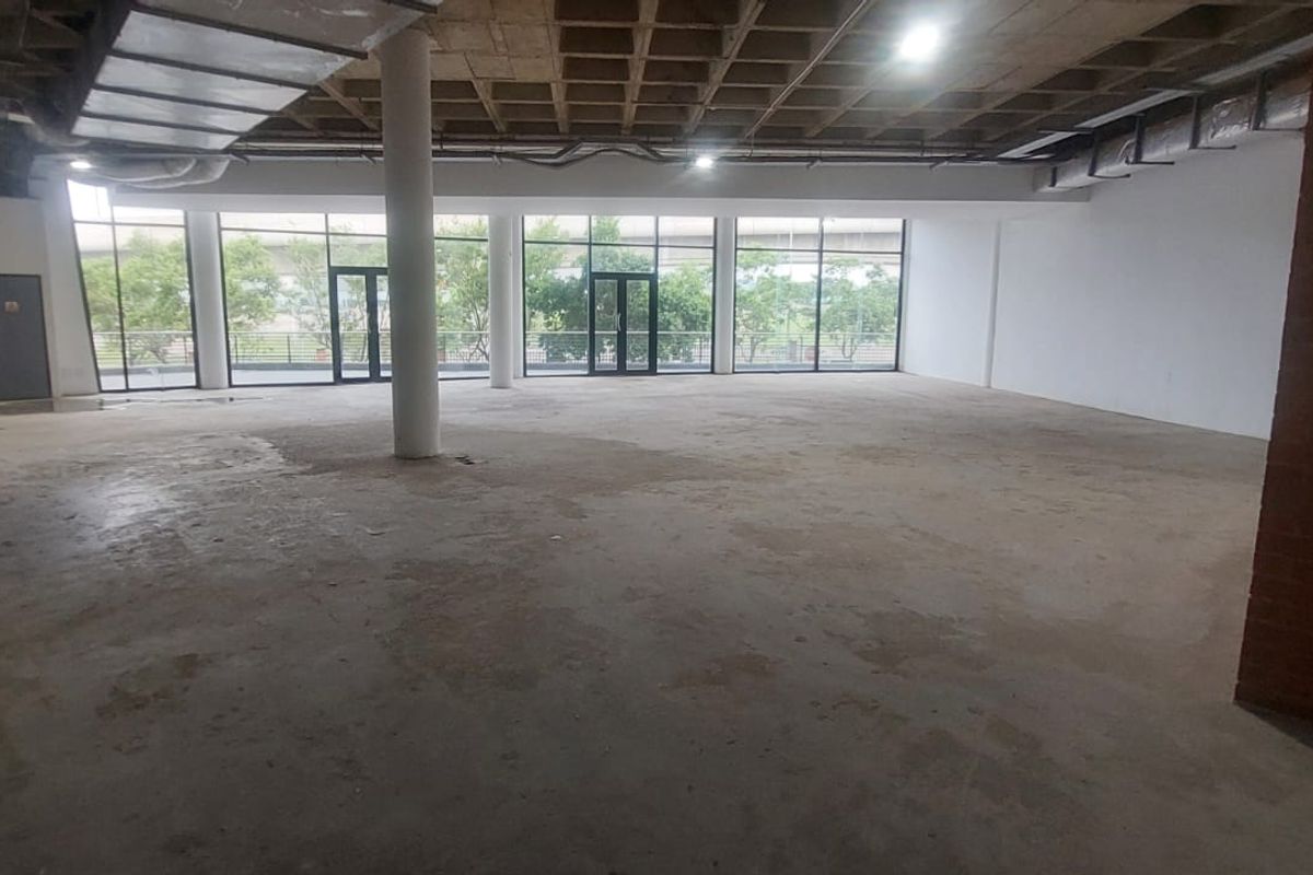 Spacious open-plan retail or commercial unit featuring an industrial aesthetic with exposed concrete waffle ceilings, ductwork, and large floor-to-ceiling windows.