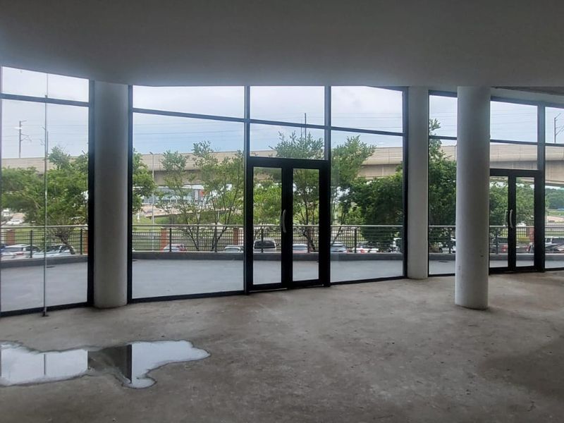 Spacious open-plan retail area featuring floor-to-ceiling glass windows, double doors, and structural columns, offering excellent natural light and visibility.