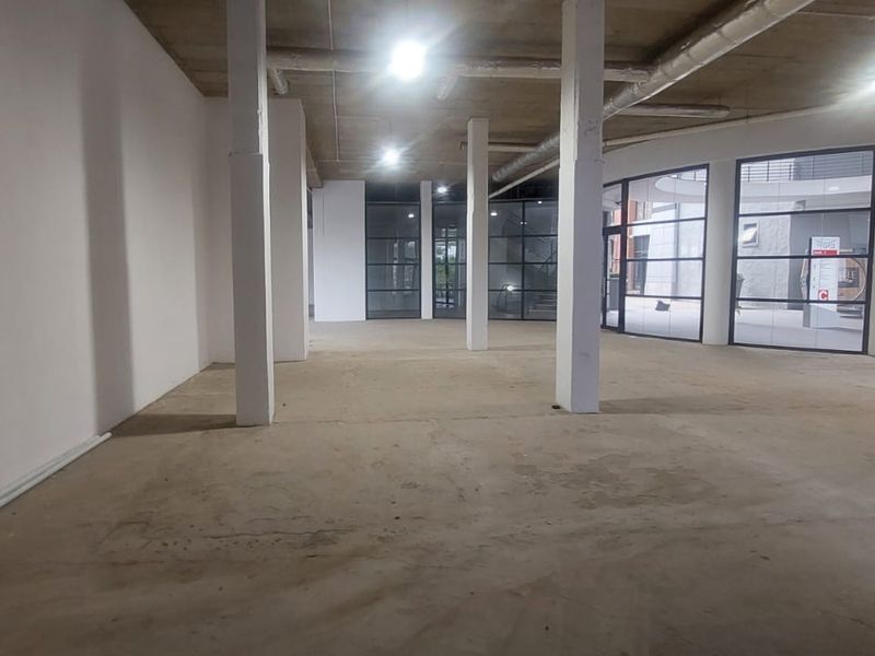 Spacious open-plan retail unit featuring exposed concrete ceilings, structural columns, and large glass storefront windows, offering a versatile blank canvas for commercial use.