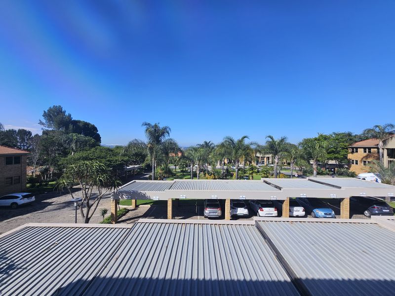 Elevated view overlooking the office park grounds, featuring covered parking bays and landscaped garden areas.