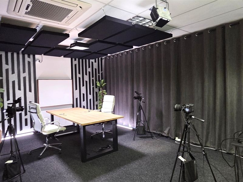 A professional office space equipped with acoustic ceiling panels, recessed air conditioning, and a whiteboard, currently set up as a media production studio.