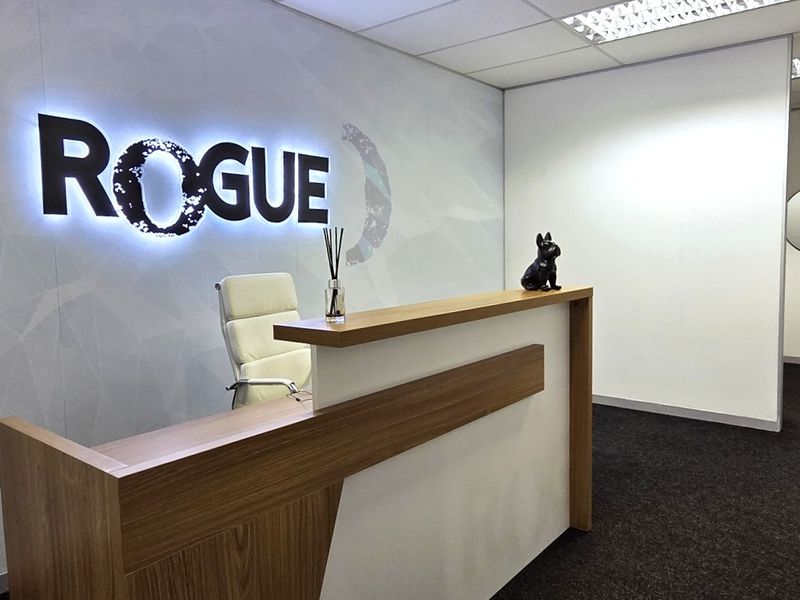 Professional office reception area featuring a modern built-in reception desk, backlit branding wall, and clean, contemporary finishes.