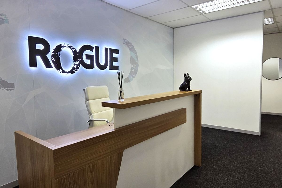 Professional office reception area featuring a modern built-in reception desk, backlit branding wall, and clean, contemporary finishes.
