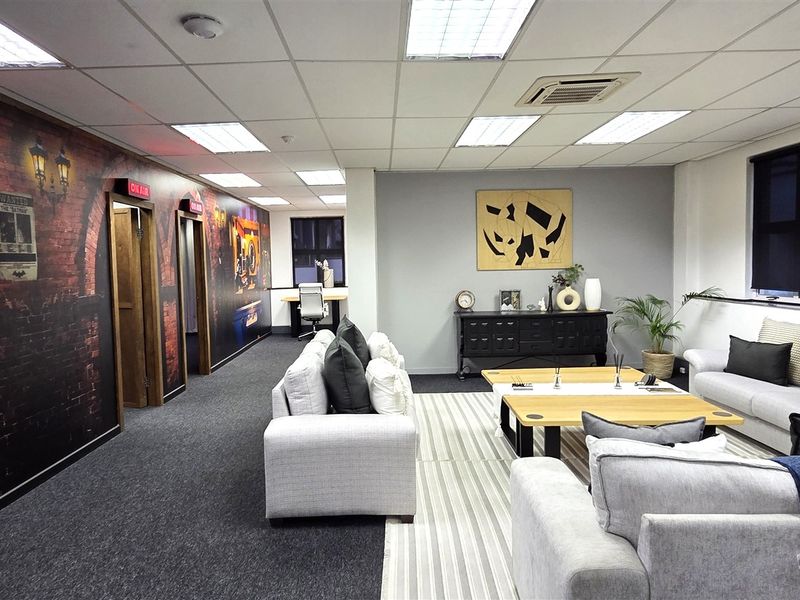 A modern, well-maintained office space featuring a suspended ceiling, recessed lighting, ducted air conditioning, and carpeted flooring with a decorative feature wall.