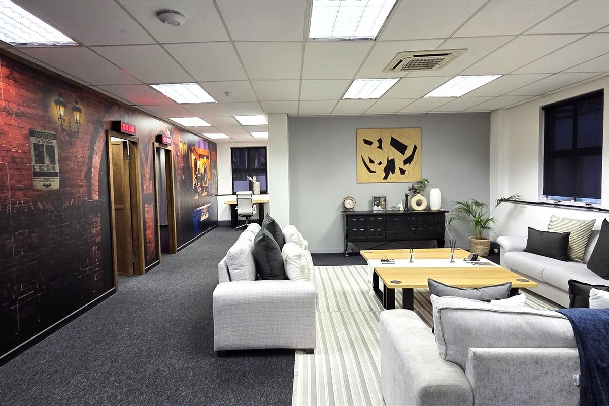 A modern, well-maintained office space featuring a suspended ceiling, recessed lighting, ducted air conditioning, and carpeted flooring with a decorative feature wall.