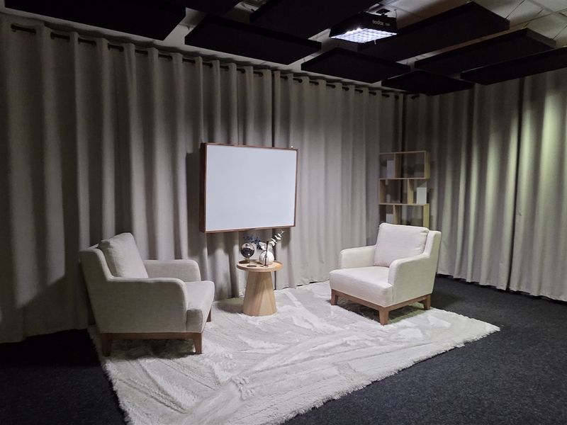 A professional office space featuring acoustic ceiling panels, recessed lighting, and a wall-mounted whiteboard, suitable for meetings or presentations.