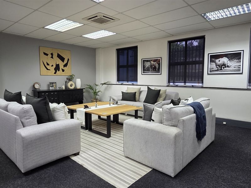 A professional office space featuring a suspended ceiling, recessed lighting, ducted air conditioning, and carpeted flooring with security bars on the windows.