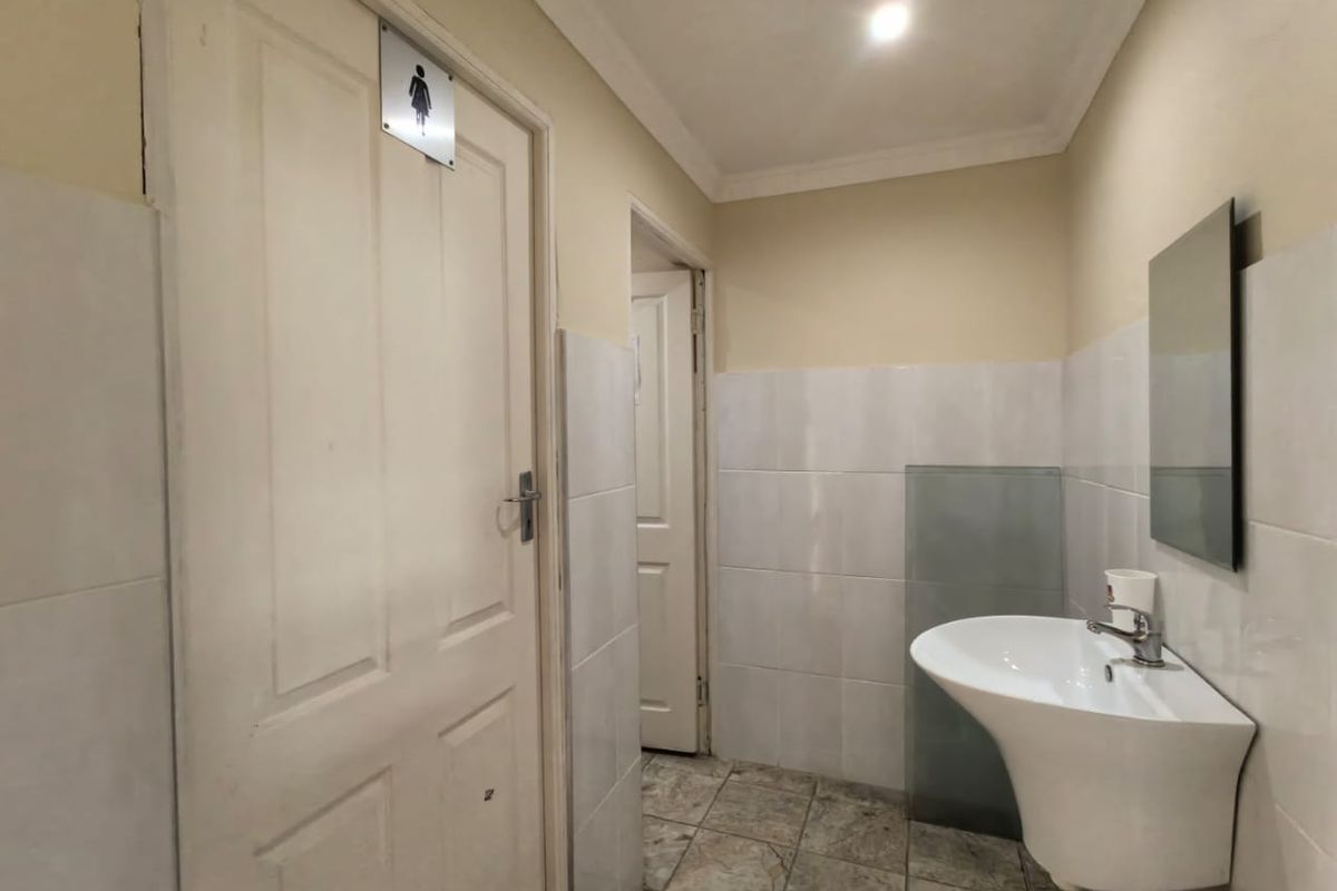 A functional commercial restroom featuring a wall-mounted basin, tiled walls, and tiled flooring, providing a clean and practical utility space.