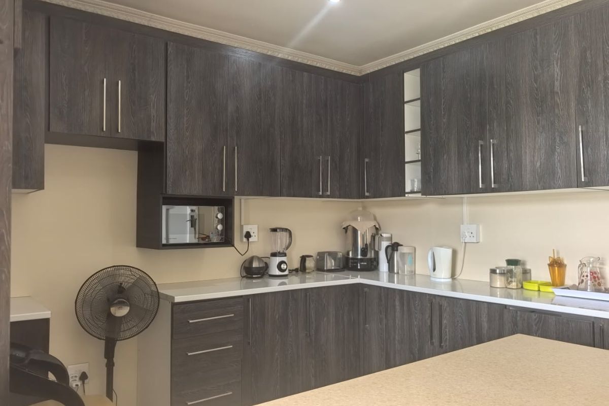 A functional kitchen featuring dark wood-grain cabinetry, white countertops, and built-in microwave housing, providing ample storage and workspace.