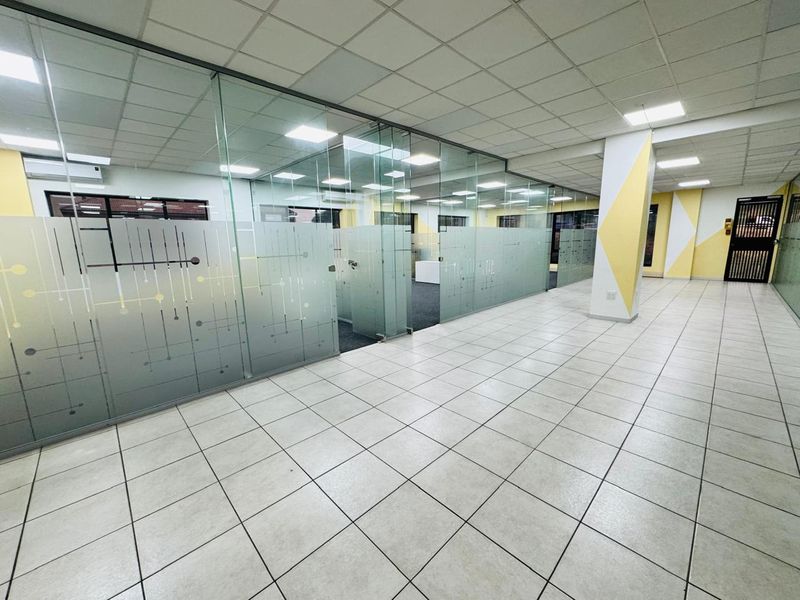 Modern office space featuring glass partitioning, suspended ceilings with recessed lighting, and durable ceramic floor tiles in a clean, open-plan layout.