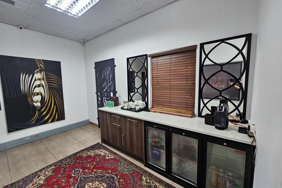 Office kitchenette area featuring built-in cabinetry, stone countertop, and integrated under-counter glass-door beverage fridges.