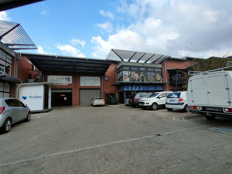 Industrial property exterior featuring a paved driveway, roller shutter doors, and brick facade with commercial signage.