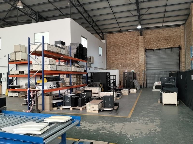 Spacious industrial warehouse unit featuring high ceilings with exposed steel trusses, roller shutter access, and durable concrete flooring.