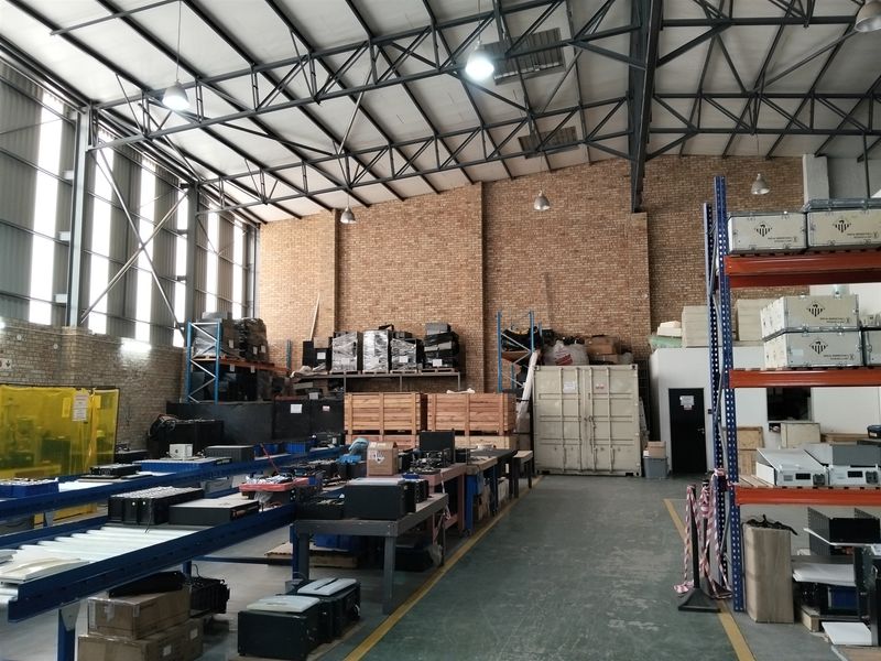 Spacious industrial warehouse featuring exposed brick walls, high steel truss ceilings, concrete flooring, and integrated heavy-duty storage racking systems.