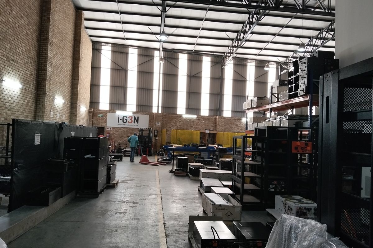 Spacious industrial warehouse facility featuring high ceilings with exposed steel trusses, concrete flooring, and natural light through translucent roof panels.