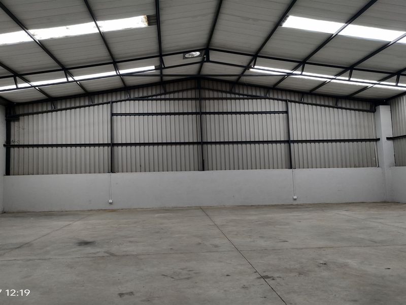 Spacious industrial warehouse unit featuring high ceilings with integrated skylights, durable concrete flooring, and robust steel frame construction.