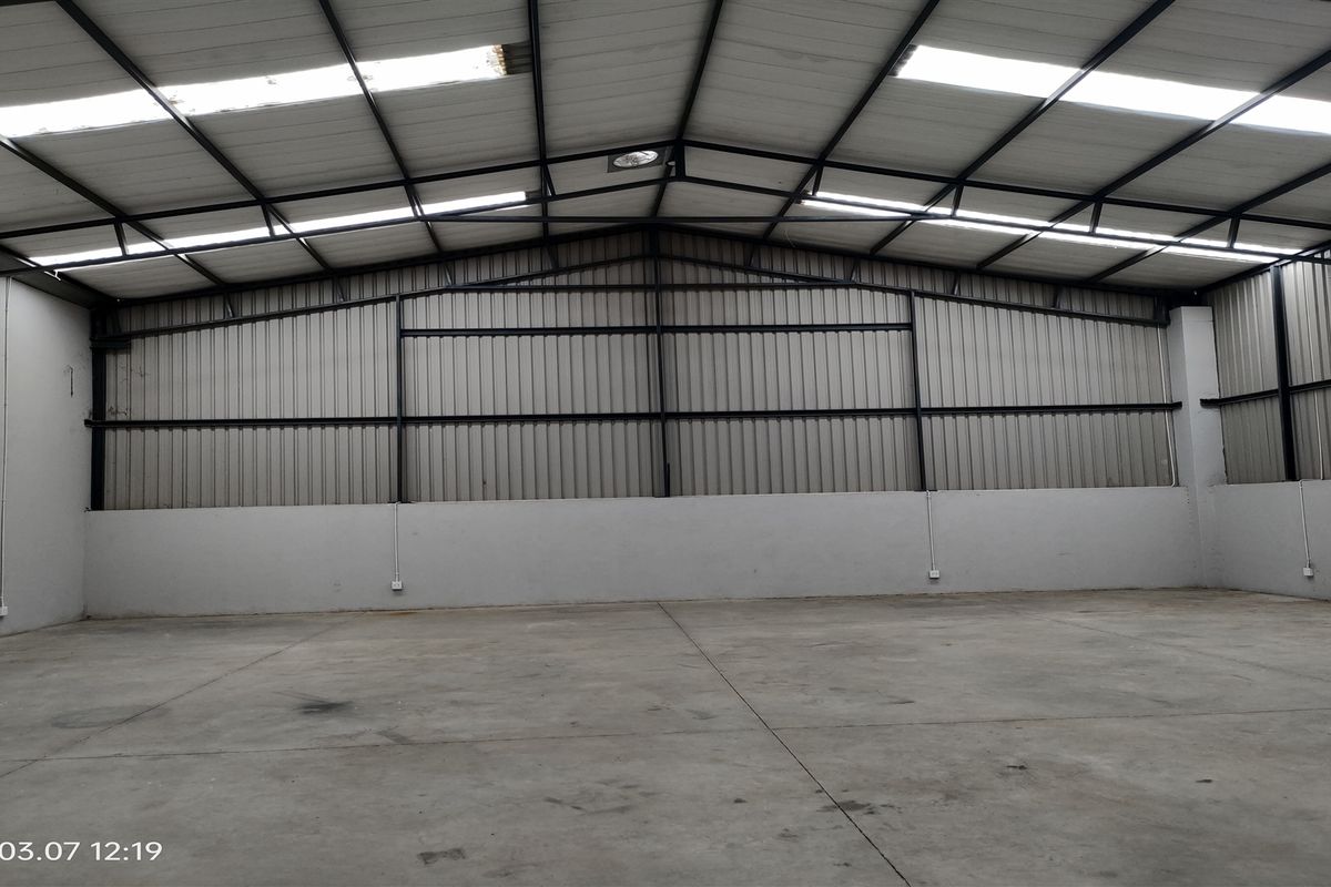 Spacious industrial warehouse unit featuring high ceilings with integrated skylights, durable concrete flooring, and robust steel frame construction.