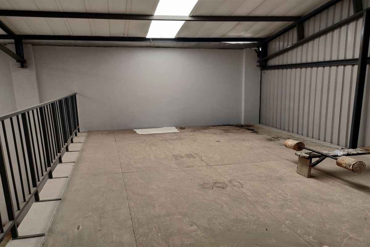 An industrial mezzanine level featuring a metal structure, corrugated wall cladding, and a skylight, providing an open utility space.