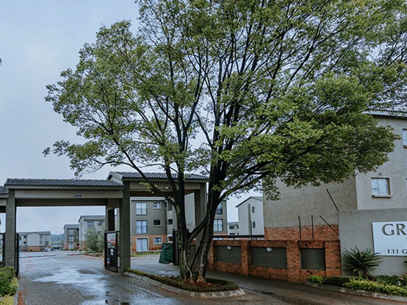 Entrance view of Greenleaf Estate featuring a gated access point, brick boundary walls, and established landscaping.